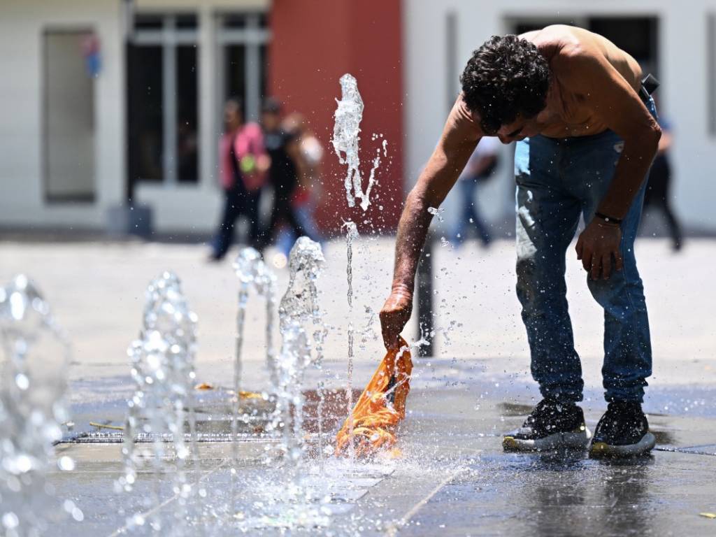 Un hombre se moja la camisa en una fuente.