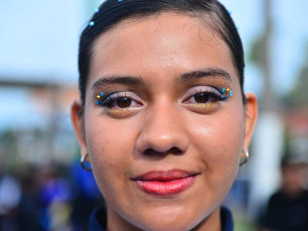 Retrato en primer plano del rostro de una estudiante con pedrería decorativa azul y dorada sobre los ojos.