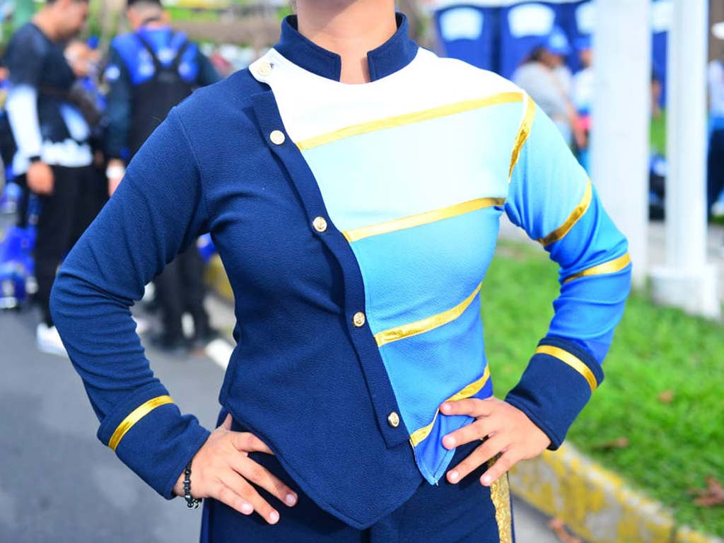 La chaqueta combina tonos azul, blanco y celeste con botones dorados y líneas cruzadas.