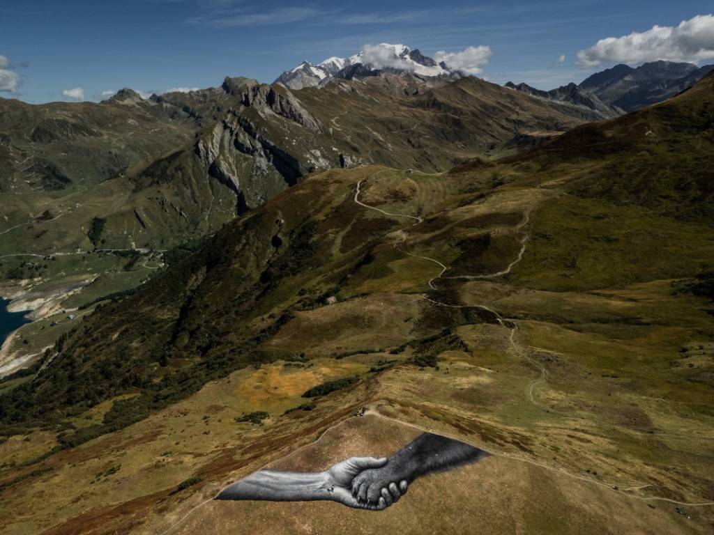 Fotografía del artista trabajando arduamente sobre el césped durante la jornada de creación de su mural alpino.
