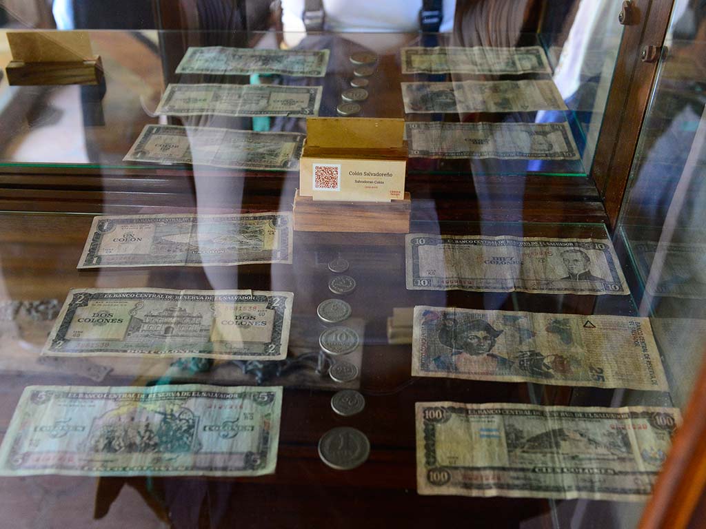 Vitrina de exhibición histórica que contiene billetes y monedas antiguas de colones salvadoreños en Casona Tunan.