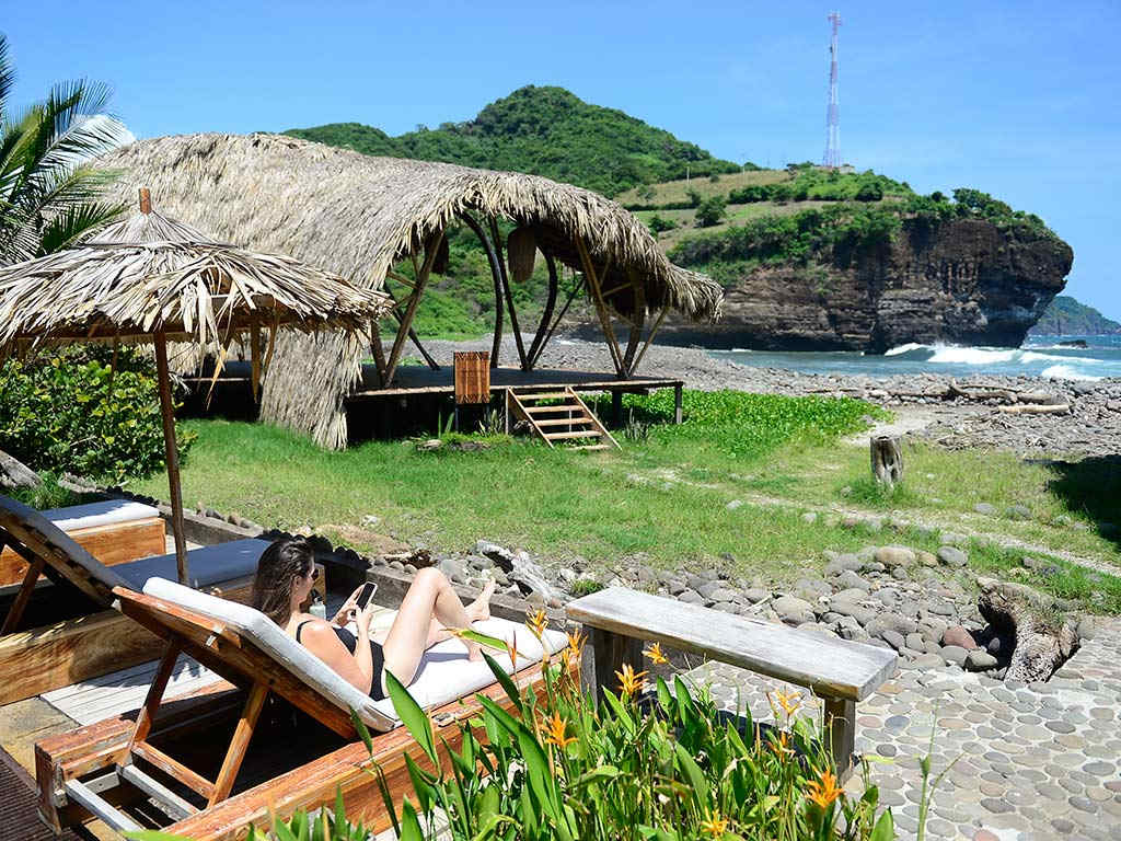Huésped descansando en una tumbona con vista a la playa, acantilados y la yoga shala frente al mar en Mizata.
