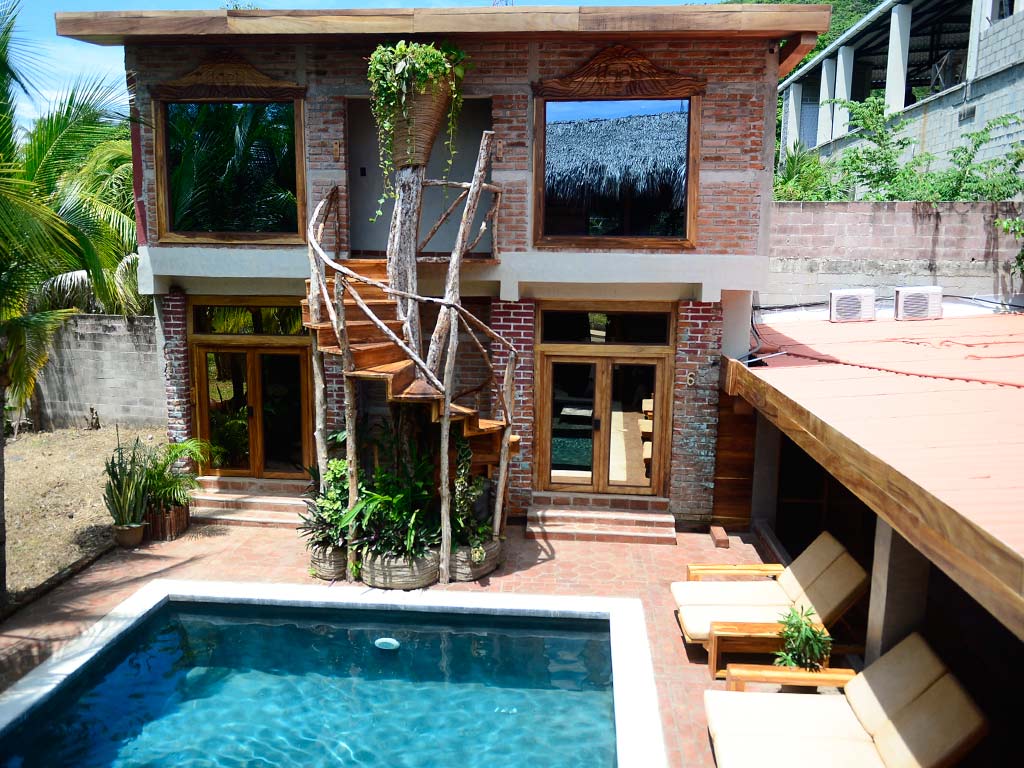 Vista aérea de la piscina privada de Casona Tunan rodeada de asoleaderos y arquitectura de ladrillo con madera en Mizata.