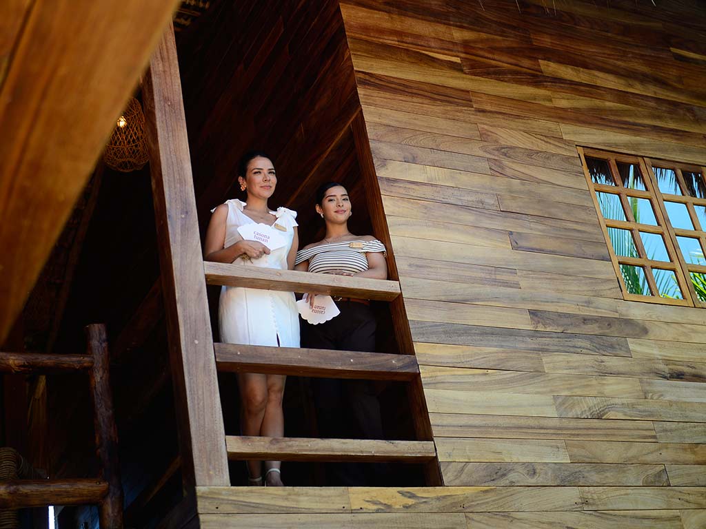 Dos colaboradoras observando la vista desde un ventanal y balcón revestido totalmente en madera de teca en Casona Tunan.