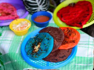Surtido de pupusas salvadoreñas de colores vivos junto a las pupusas de masa de frijol.