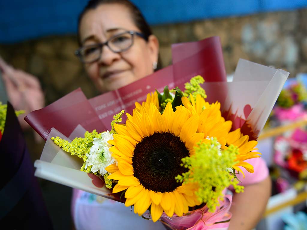 Ana del Carmen Alvarado atiende en su floristería sobre la 29 Calle Oriente mostrando los girasoles y rosas amarillas más pedidos.
