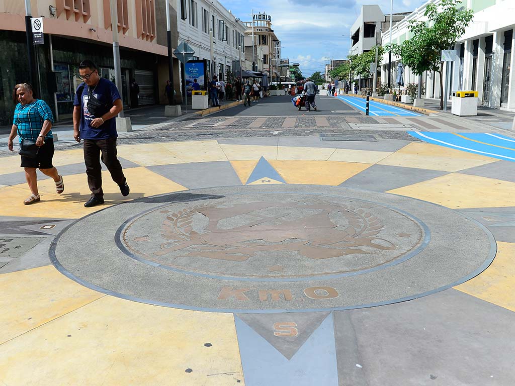 Detalle arquitectónico de encaje metálico y patrones geométricos en el pavimento del Kilómetro Cero.
