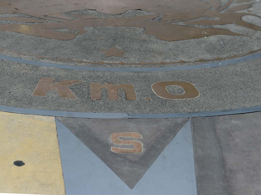 Detalle en primer plano de la letra Km 0 en bronce sobre la rosa de los vientos en el suelo.