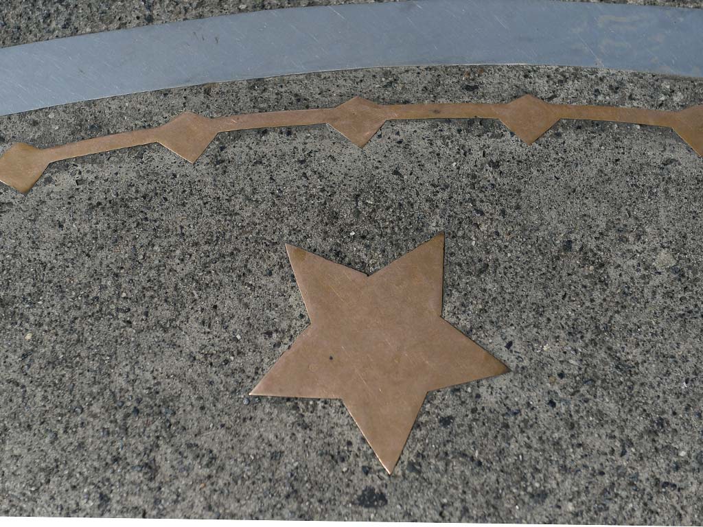  Incrustación de una estrella de bronce en el pavimento gris junto al círculo del Kilómetro Cero.