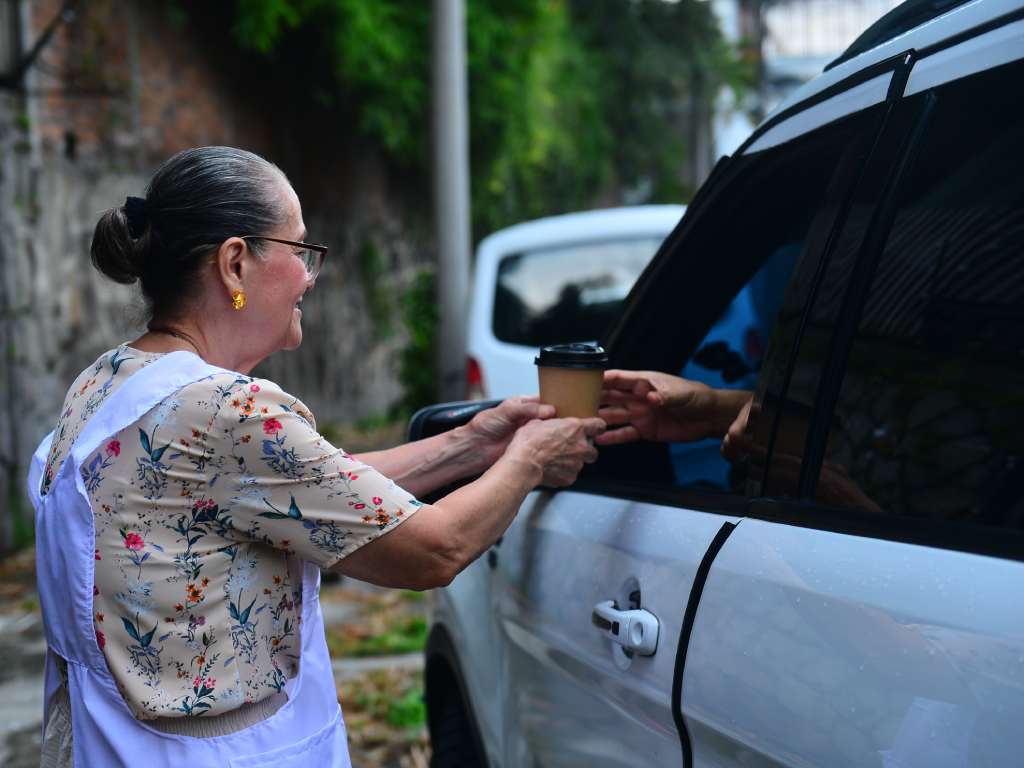 Mamá Tere entrega un vaso de atol a un cliente en su local de la colonia San Benito.