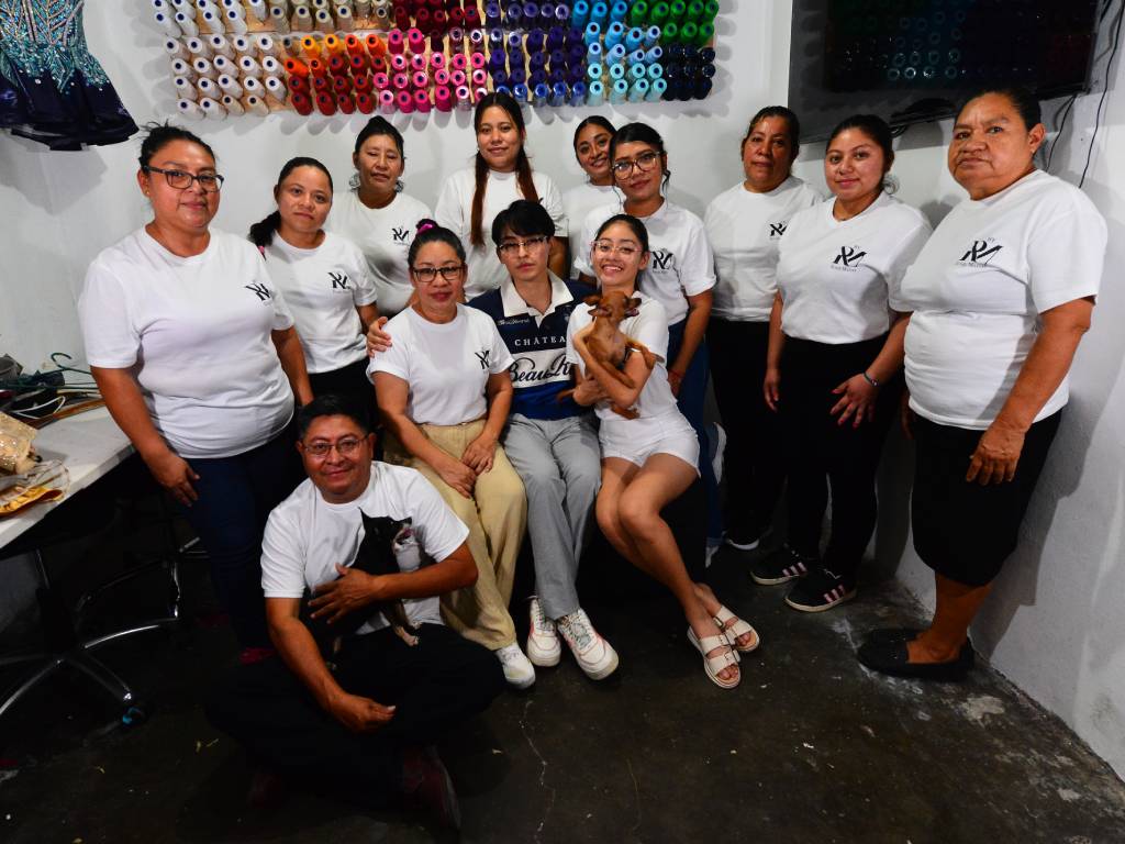 El equipo completo de Roni Matías sonriendo y posando agrupado dentro del taller rodeado de trajes y herramientas.