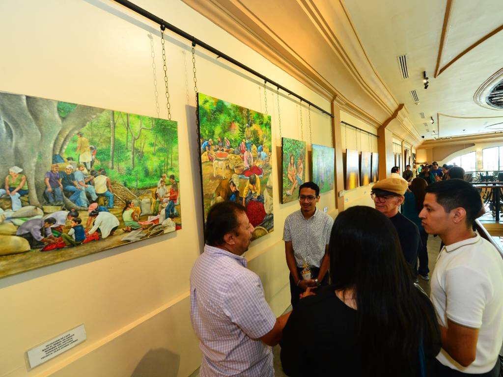 Germán Sagastume conversando amablemente con un grupo de visitantes en la sala de la exposición.