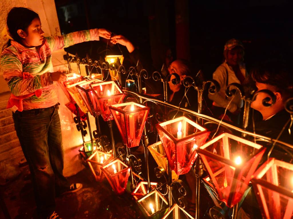 Personas recibiendo farolitos artesanales encendidos frente a las instalaciones de la alcaldía de Ataco.