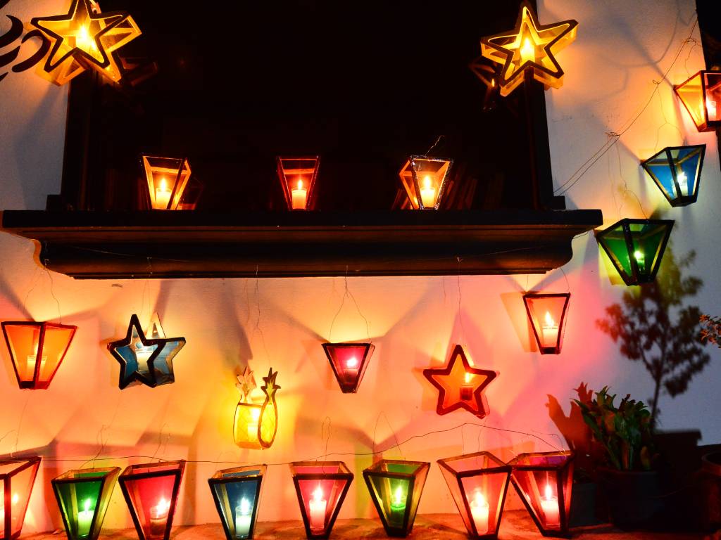 Pared de un establecimiento comercial decorada con hileras de farolitos multicolores encendidos.
