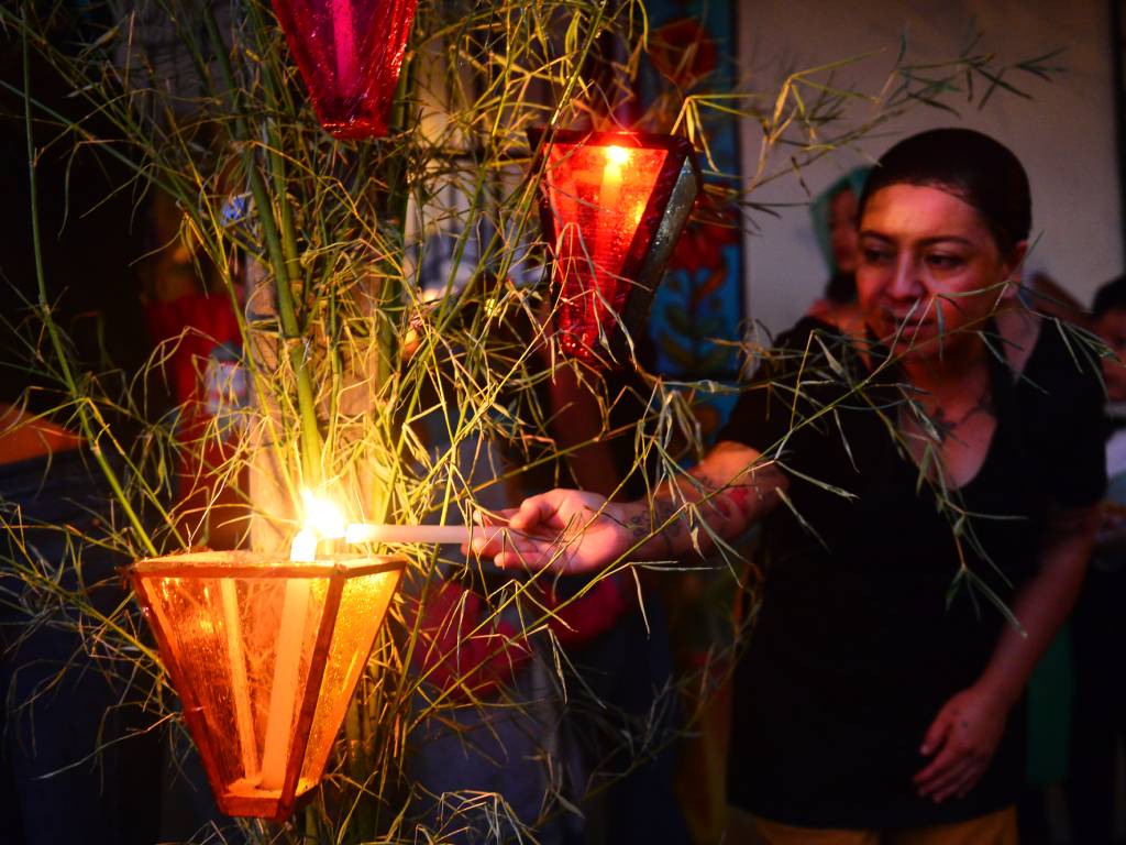Vista nocturna de una calle adornada con farolitos artesanales encendidos en las fachadas.