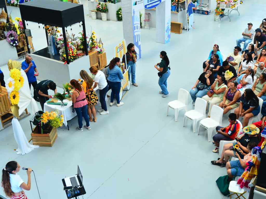Comerciantes preparando arreglos y transeúntes recorriendo los puestos la jornada previa al evento principal.