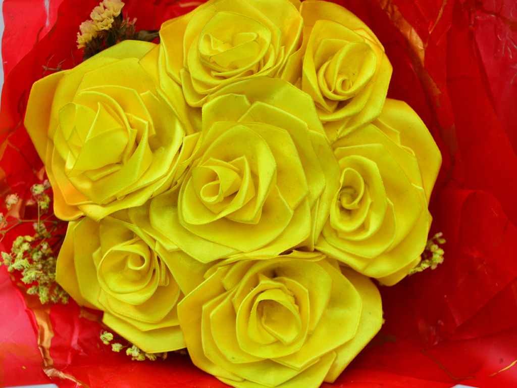 Detalle de un arreglo de rosas eternas amarillas con su etiqueta de precio de 10 dólares en el local.