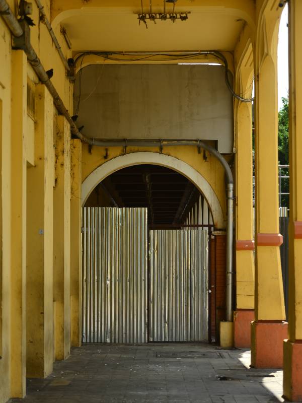 Vista de cerca del pasillo interior del Portal Sagrera en construcción, mostrando una valla de lámina galvanizada cerrando el acceso bajo un arco.