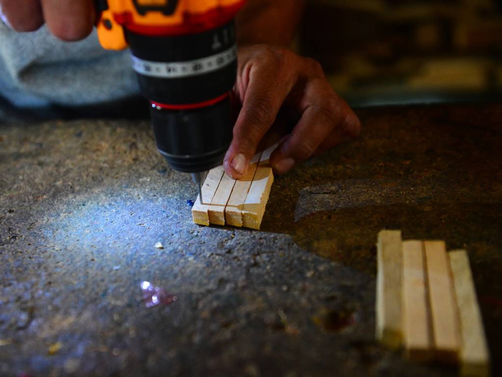 Con un taladro se perforan las piezas de madera para continuar con el ensamblaje de los farolitos. (