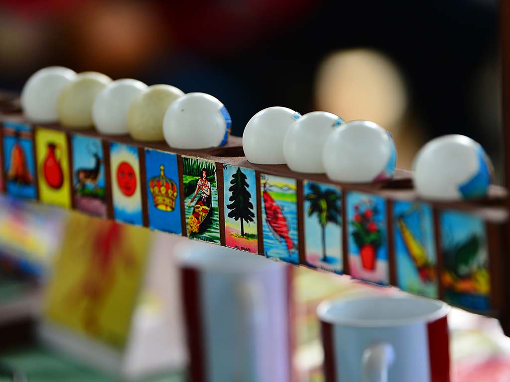 Serie de esferas numeradas con dibujos tradicionales alineadas sobre un soporte de madera.