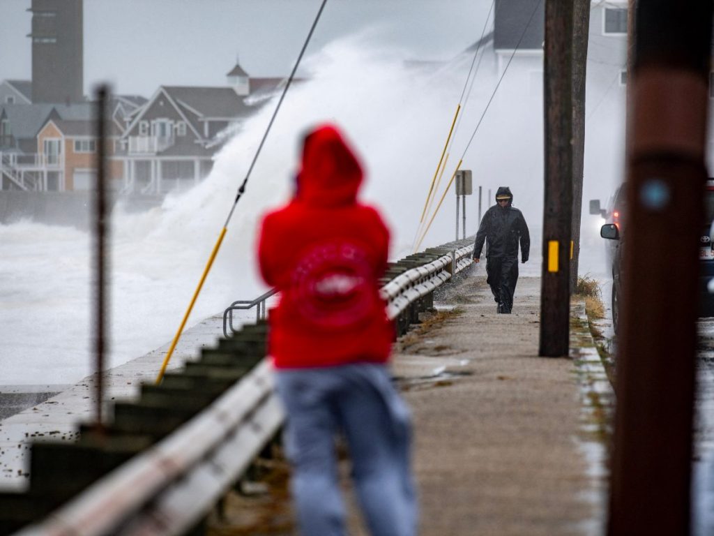 Varias personas recorren la costa de Scituate, Massachusetts, mientras una potente tormenta provoca fuerte oleaje en el noreste de EE.UU.