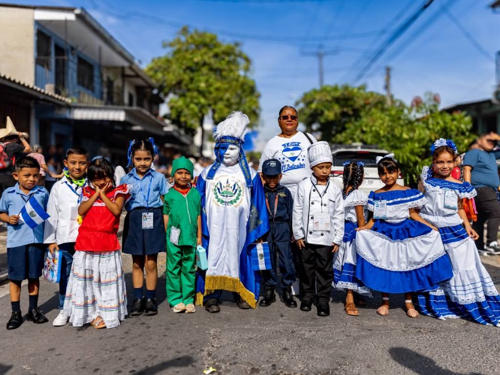 Niños y niñas con trajes de distintas profesiones posan sonrientes para la cámara junto a sus docentes antes de marchar.