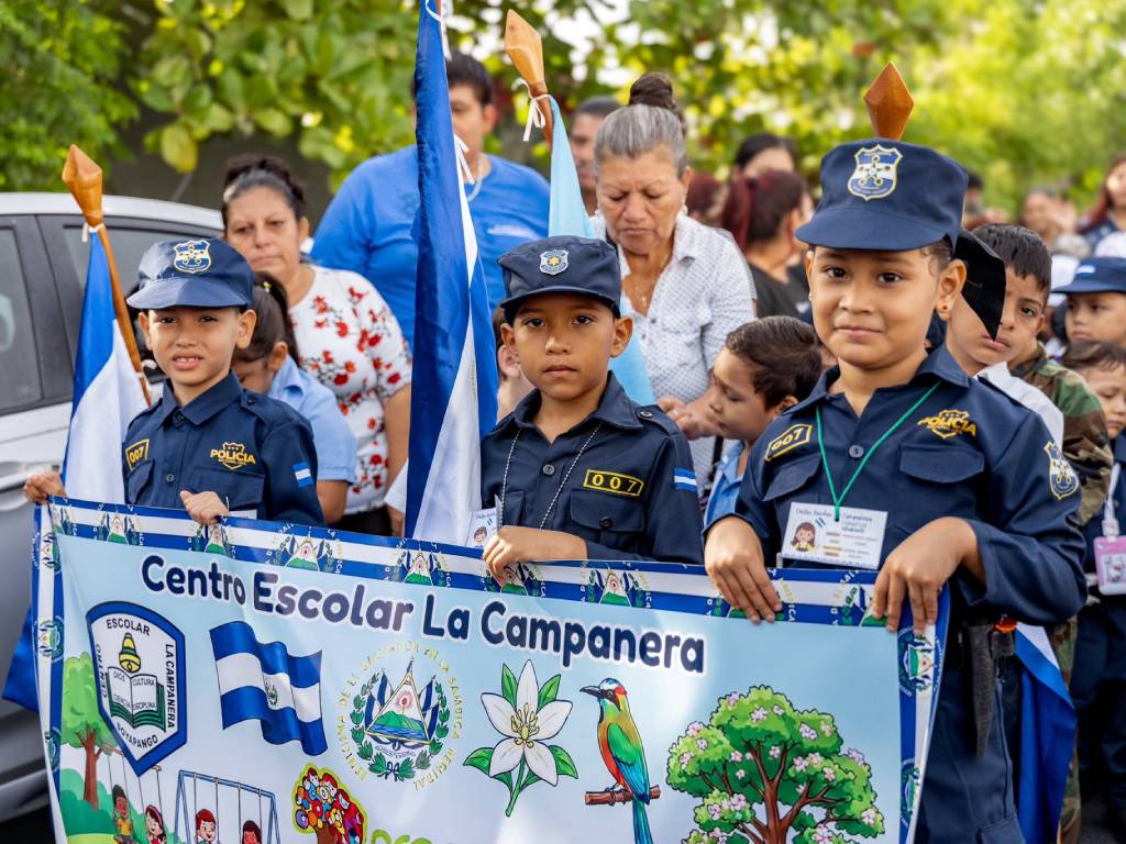 Estudiantes vestidos con uniformes de la policía marchan de manera ordenada por la calle durante el desfile cívico.