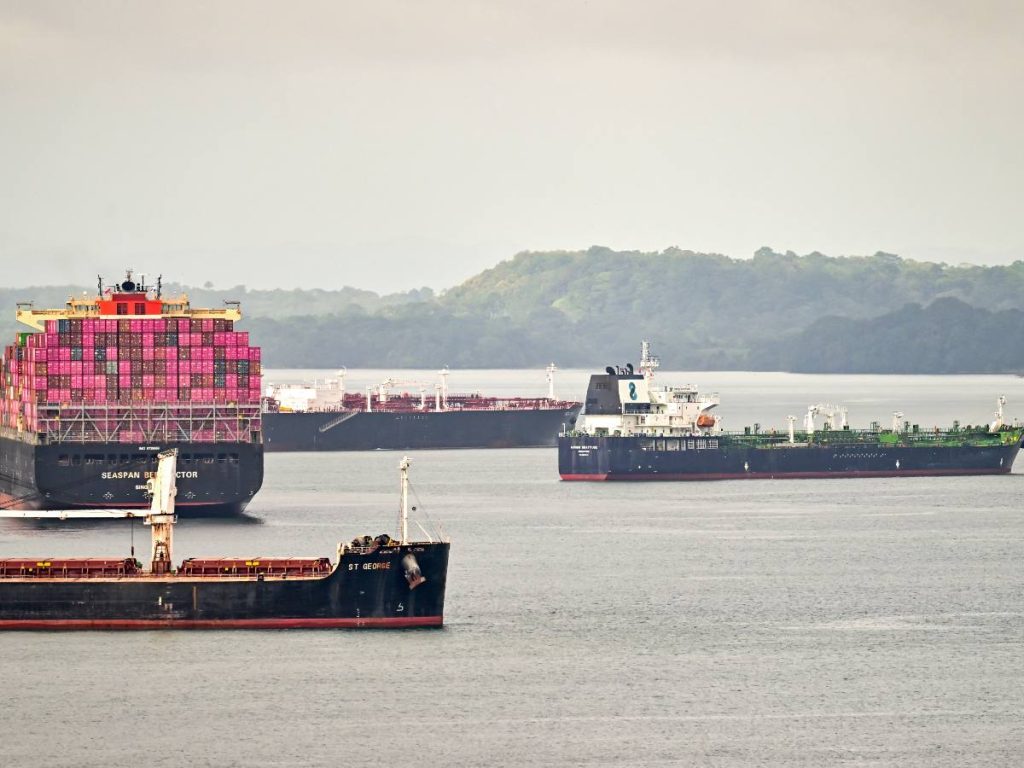Buques de carga atraviesan el Canal de Panamá, que reducirá el tránsito diario y podría elevar costos logísticos para exportadores salvadoreños.