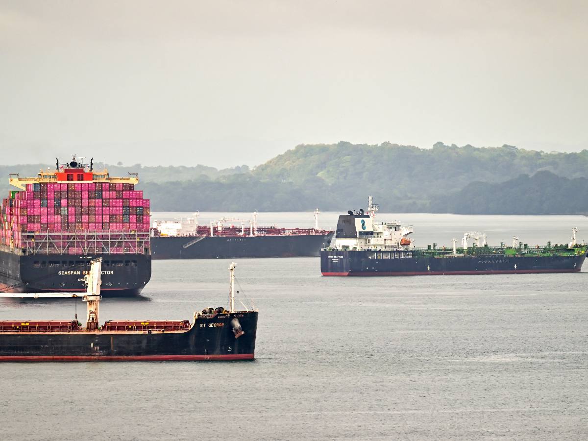 Buques de carga atraviesan el Canal de Panamá, que reducirá el tránsito diario y podría elevar costos logísticos para exportadores salvadoreños.