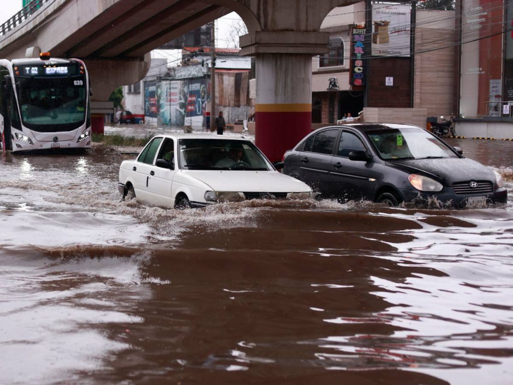 Fotografía que muestra vehículos transitando por una calle inundada debido a las fuertes lluvias este martes, en Pachuca (México). EFE