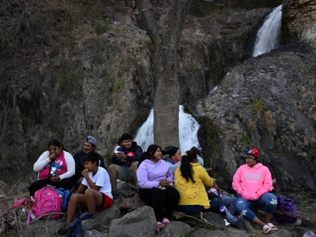Excursionista descansando sobre unas rocas cerca de la cascada tras completar el recorrido de montaña.