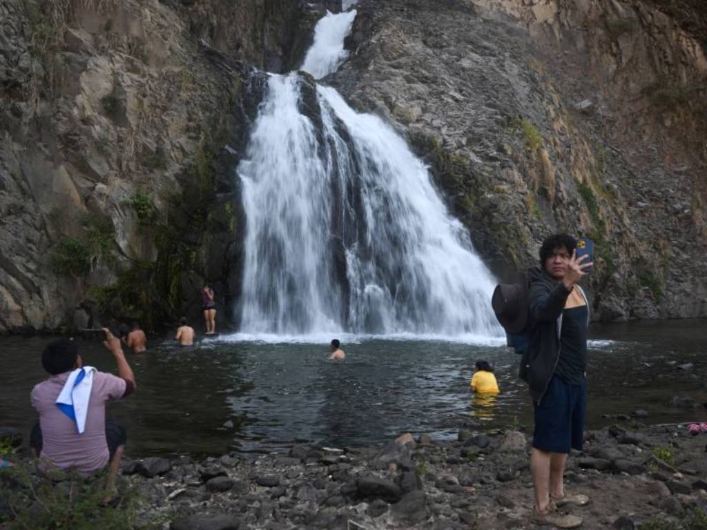 Grupo de excursionistas caminando por un sendero natural rodeado de vegetación y paisajes montañosos.