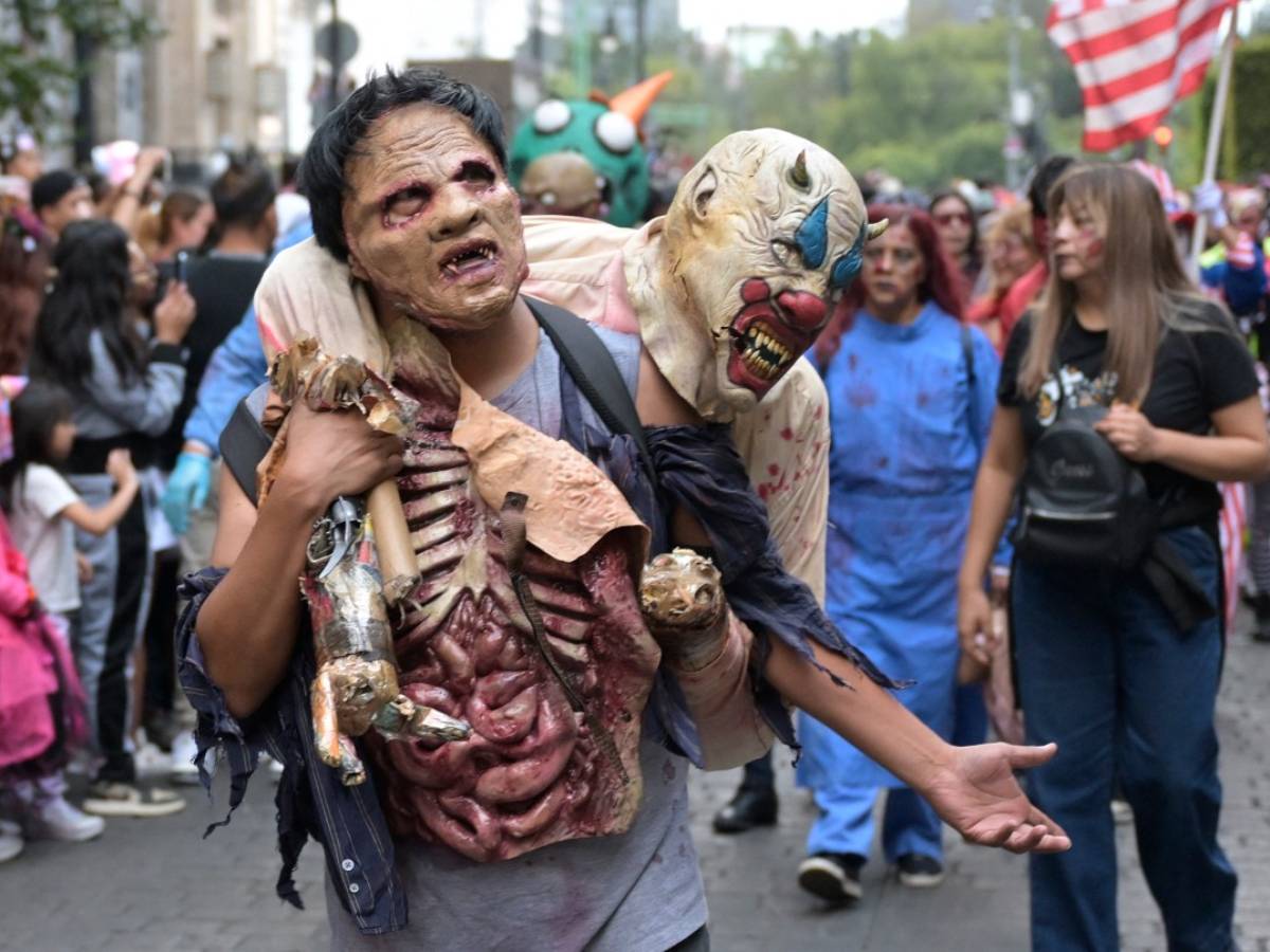 Integrantes del desfile avanzando organizadamente en bloques temáticos de caminantes y criaturas de terror hacia la plaza principal.