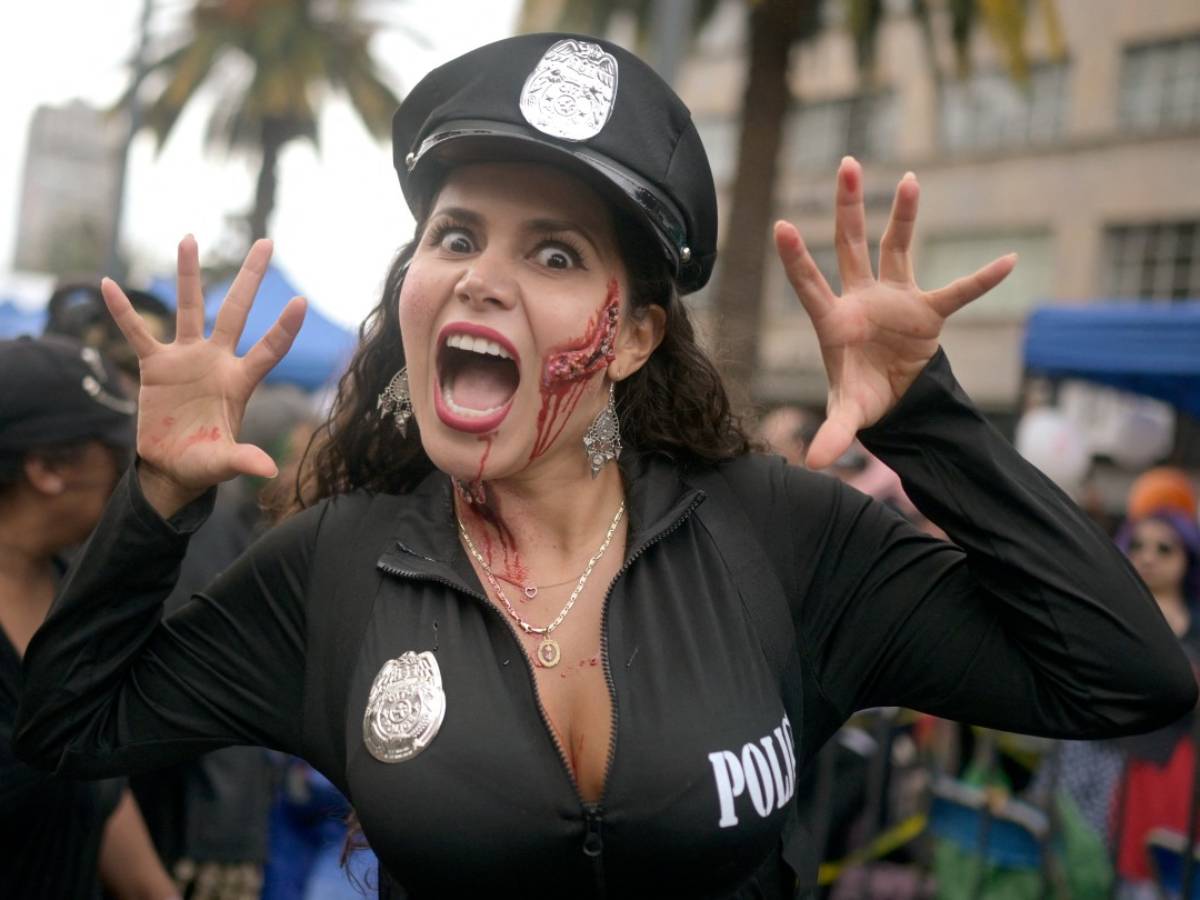 Mujer caracterizada como policía zombie con maquillaje de herida sangrienta en el rostro expresando un gesto de susto.
