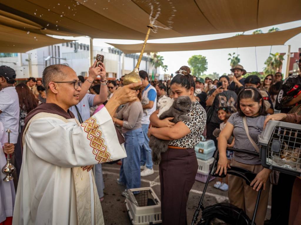 Creyentes congregados en el patio de un templo parroquial reuniéndose para la bendición ceremonial de sus mascotas.