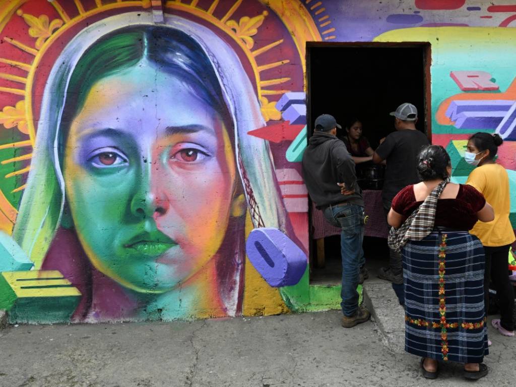 Grupo de artistas trabajando en la elaboración de murales comunitarios sobre paredes de la localidad.