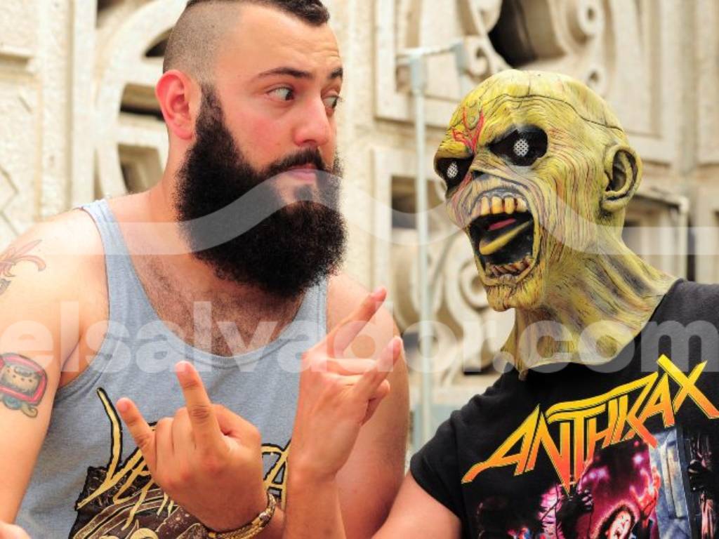 Un fanático vistiendo una máscara de Eddie, mascota de Iron Maiden, junto a otro seguidor haciendo el gesto del rock.