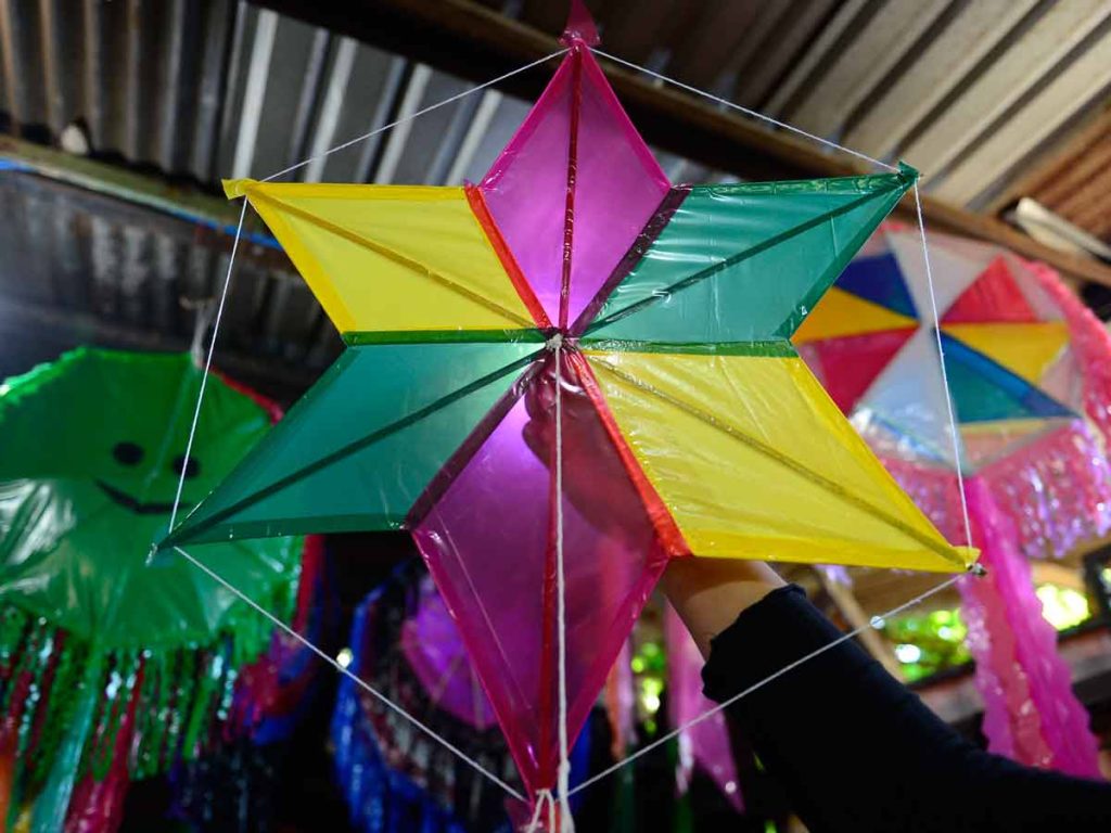 Persona sosteniendo en el aire una piscucha con forma de estrella de seis puntas en colores amarillo, verde, magenta y transparente
