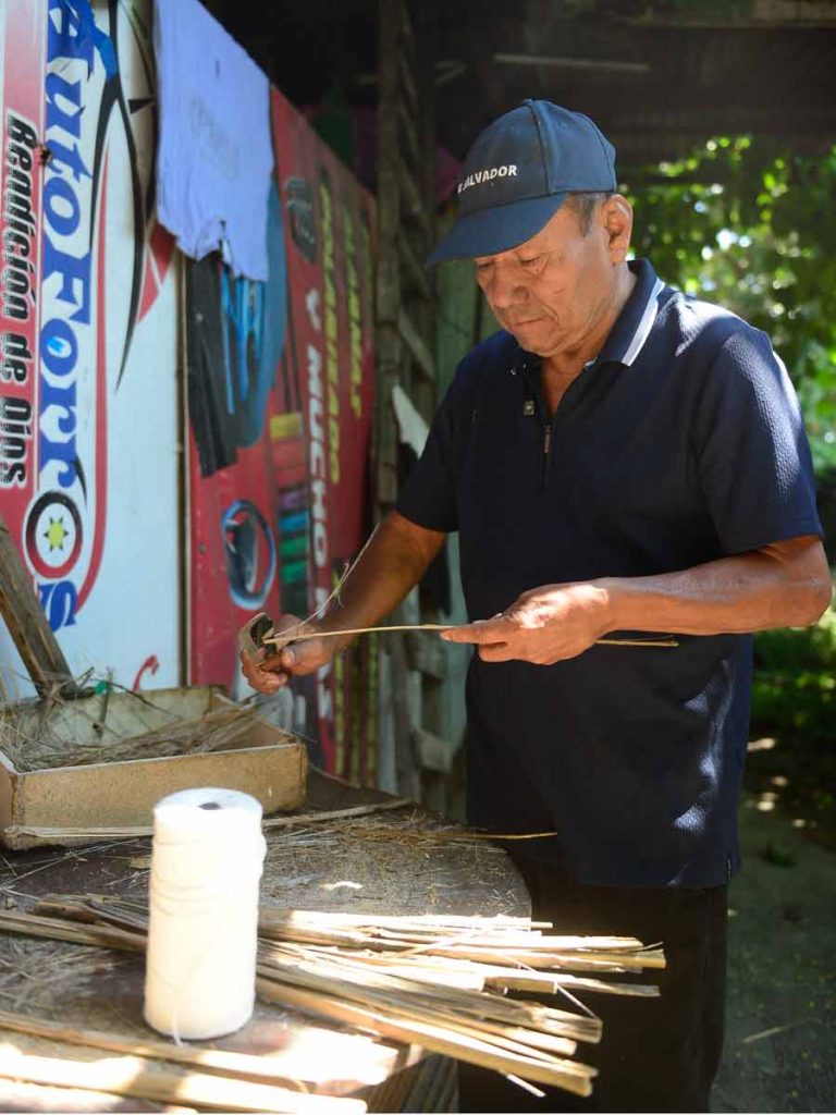 Don Ramiro Peinado raspando y preparando con delicadeza una vara fina de bambú sobre su mesa de trabajo