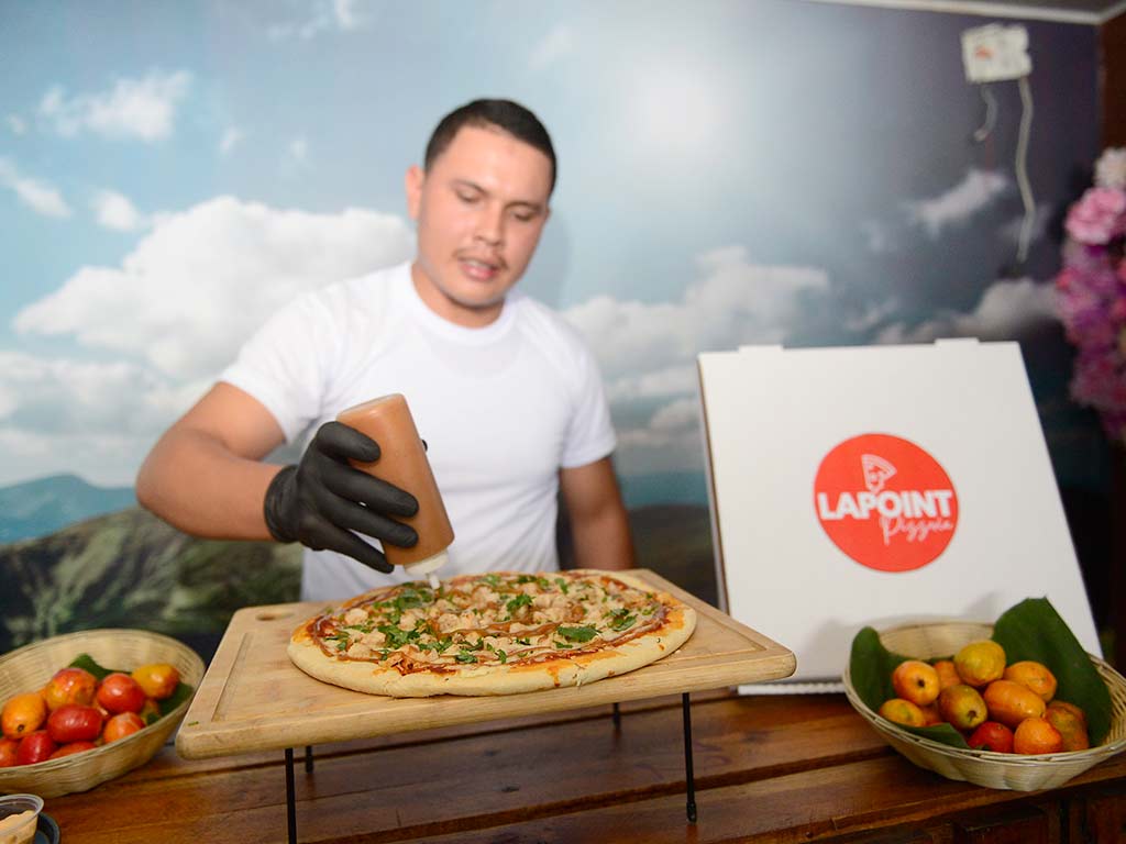 Elaboración en vivo de pizza artesanal aderezada con salsa de jocote de corona por un cocinero local.