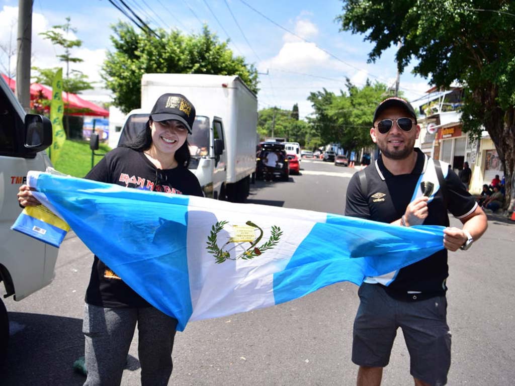 Pareja de fanáticos desplegando la bandera nacional de Guatemala en la calle cerca del estadio.