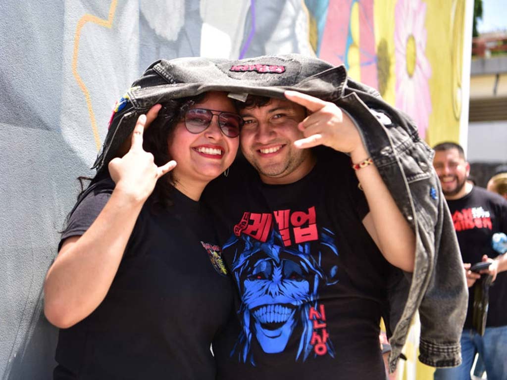 Hombre y mujer sonriendo y haciendo la seña del rock mientras se cubren la cabeza con una chaqueta de jeans.