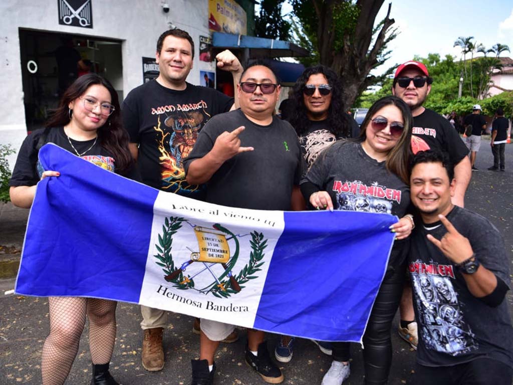 Grupo de jóvenes posando en la calle con camisetas de bandas de metal y desplegando la bandera de Guatemala.