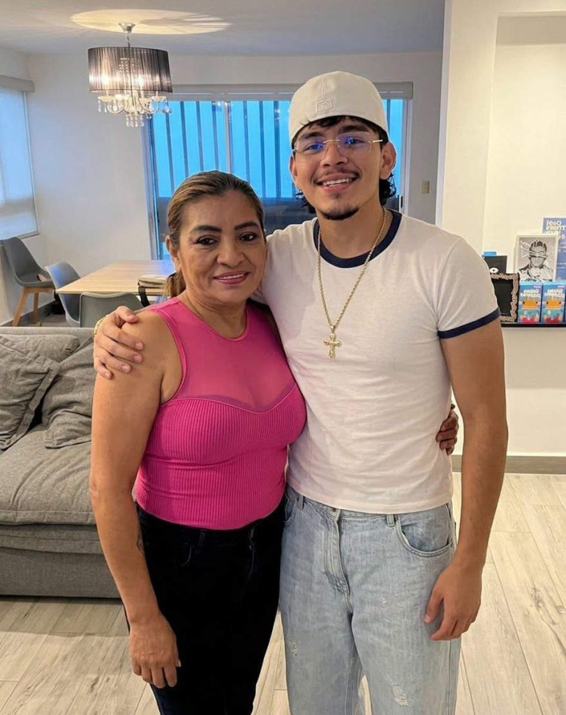 El Komanche abrazando a la niña Yani dentro de un apartamento con sonrisa cálida.