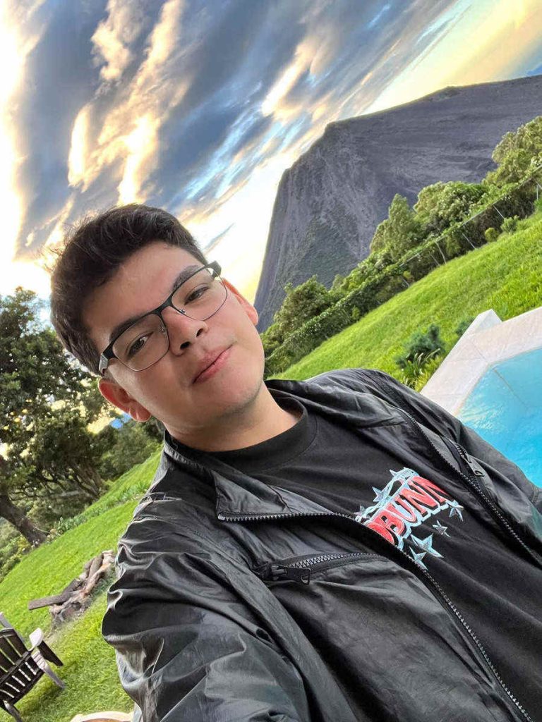 Selfie de El Komanche en una piscina con vista al volcán de Izalco y el cielo al atardecer.