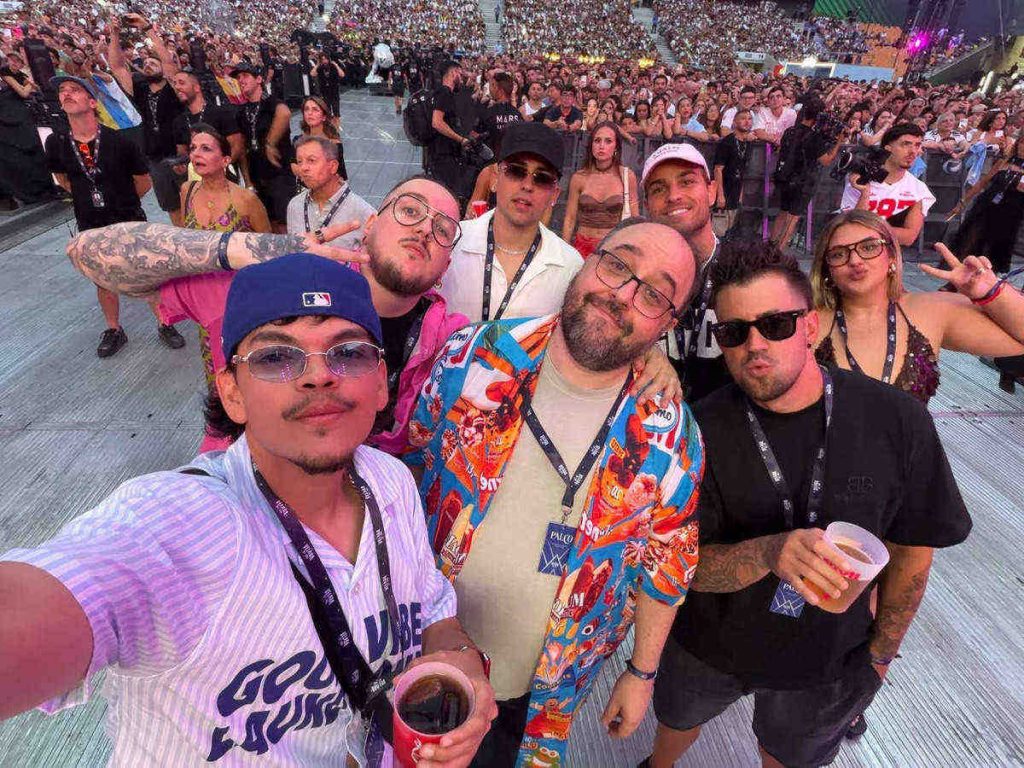 El Komanche en primer plano tomando una selfie con un grupo de streamers famosos en un estadio abarrotado.