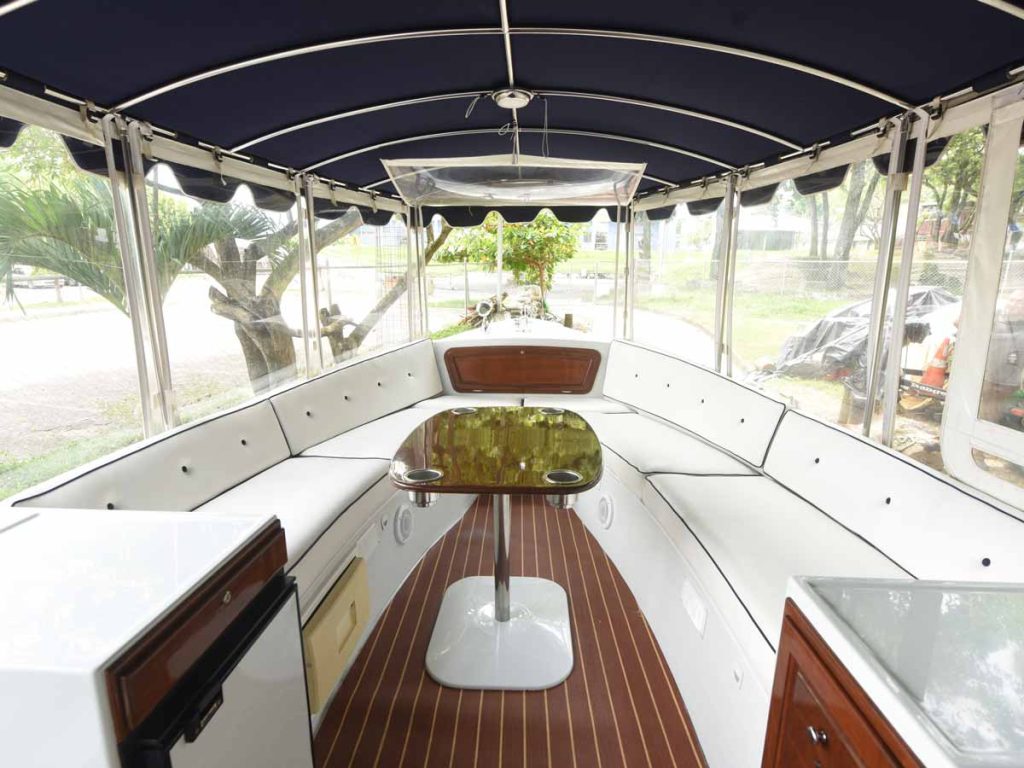 Interior de un barco de lujo con asientos acolchados y mesa para recorridos por el Lago de Ilopango