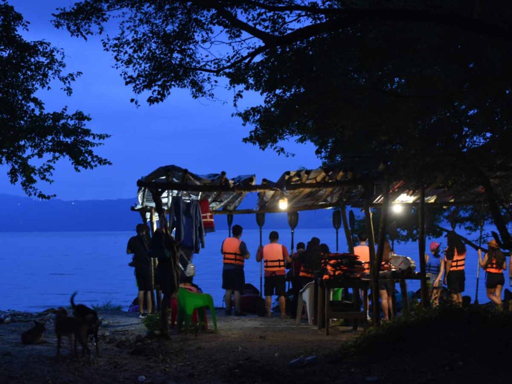 Turistas con chalecos salvavidas preparándose para ver el amanecer a la orillas del Lago de Ilopango
