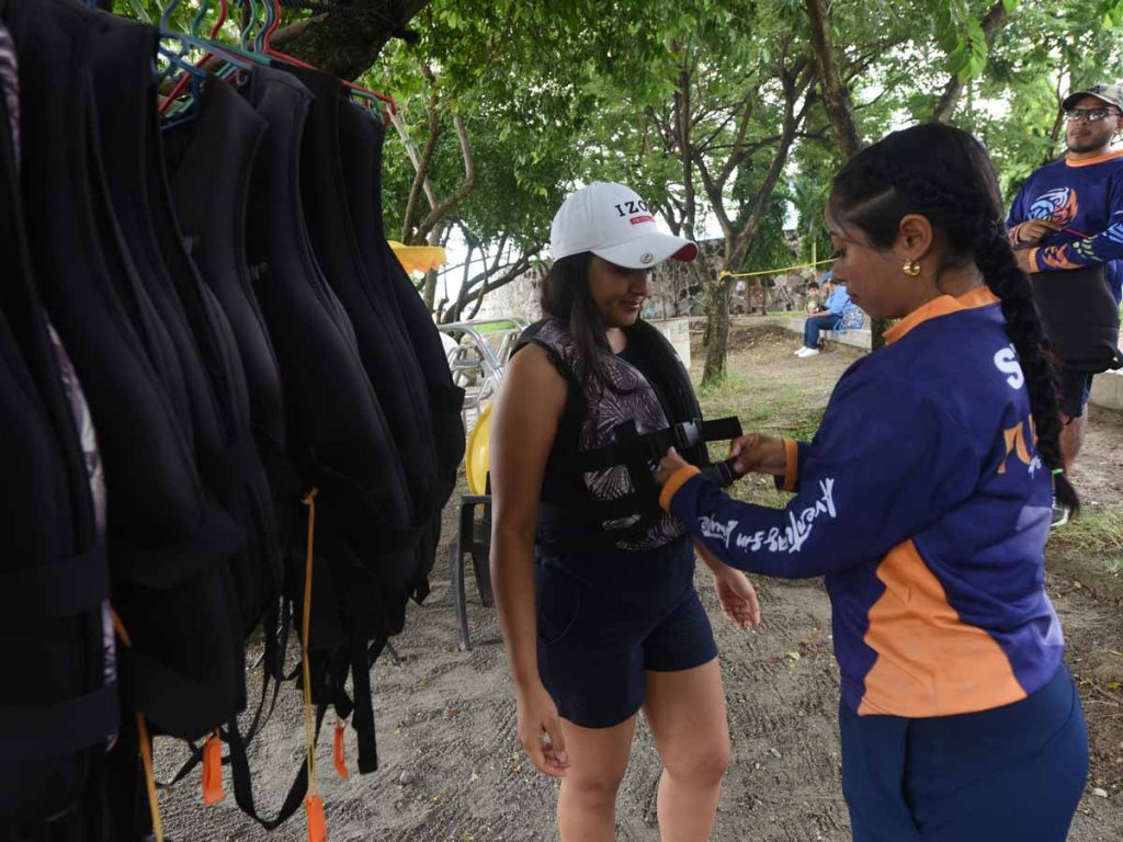 Instructora colocando chaleco salvavidas a una turista antes de realizar juegos acuáticos en Ilopango