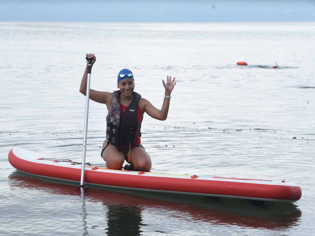 Mujer practicando paddleboard o remo de pie con chaleco salvavidas en el Lago de Ilopango